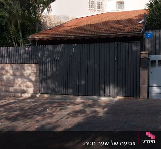 גדר עץ צבועה בצבע כהה ליד בית